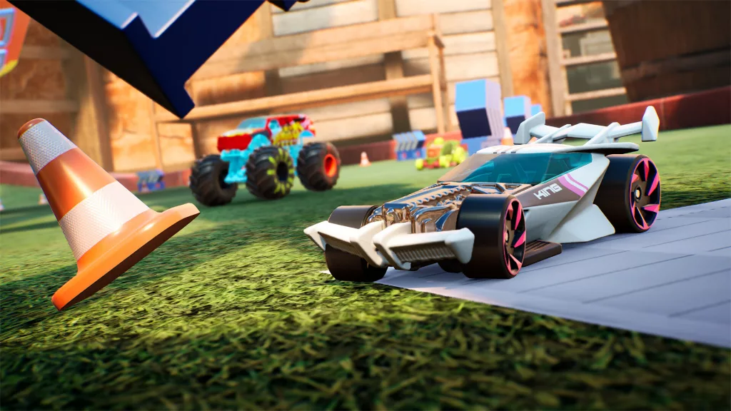 Hot Wheels Unleashed 2 gameplay showing a sleek white car with pink wheels racing on a grassy track near a toy traffic cone.