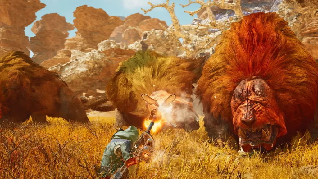 A hunter in a green hooded cloak wields a massive, glowing hammer-like weapon against colossal, lion-like beasts with fiery manes in a dry, rugged landscape. The creatures snarl menacingly, their thick fur bristling as they prepare to strike. The terrain is filled with golden grass, twisted trees, and towering rock formations under a bright, clear sky.