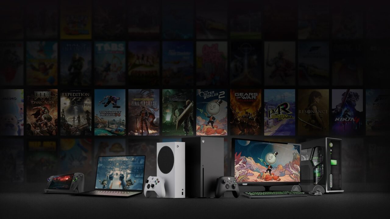 Xbox Series X, a gaming PC, a laptop and a handheld in front of a wall of game covers