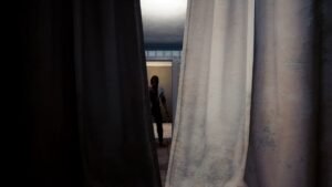 The Transference screenshot: a hallway with white curtains and a figure in the distance